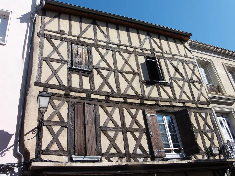 Maison à pans de bois rue Armand Caduc à La Réole, avec colombages sombres, volets en bois et façade voisine en pierre.